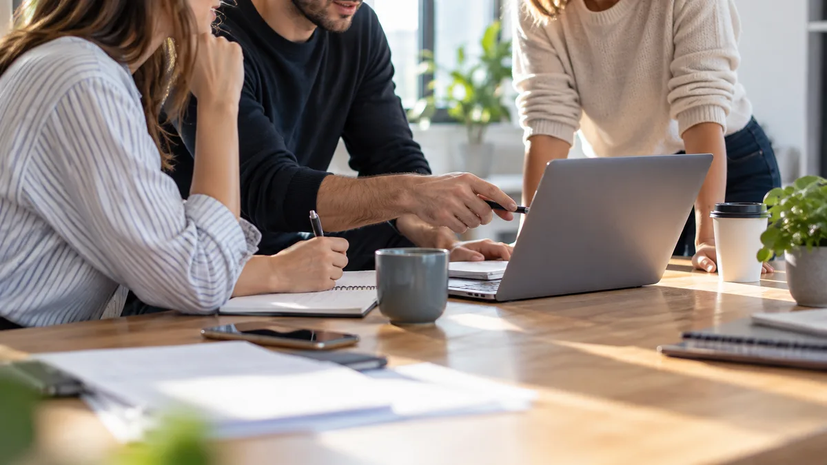 pequeño equipo reunido alrededor de una mesa con un portátil (horizontal)